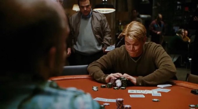 A young man with blonde hair sits at a casino card table, smiling as he handles chips and cards, with another man standing behind him observing the game. The image of a poker scene visually mirrors the post's metaphor of "high stakes" and risk-taking, echoing the poster's anxiety about a volatile gamble that could backfire despite confidence from others around him.