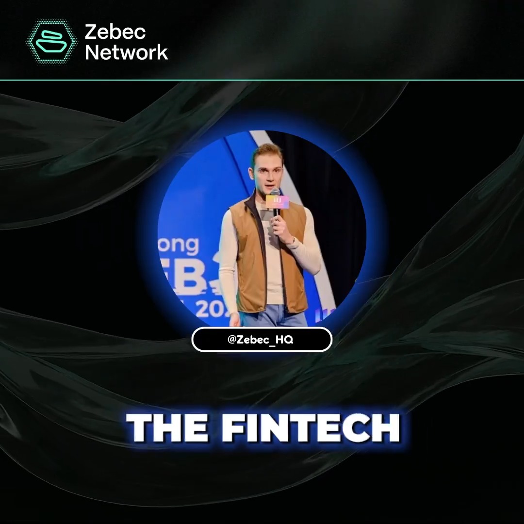 The image features a man standing behind a microphone, holding a microphone stand with his hand raised high above it. The background of the image is black, which contrasts with the white text that reads "The Fintech" at the top center of the image. Below this title, there are two lines of white text: one reading "Zebec Network" and another saying "@simonb_ldn". These texts provide information about the person speaking in the image and the platform they are associated with.