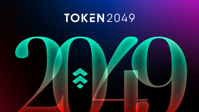 The image displays a promotional graphic for TOKEN 2049, featuring the event name in clean white text at the top and a large stylized "2049" in teal gradient below against a dark, geometric background with red accents. It visually sets the anticipation for the crypto conference mentioned in the post, signaling the upcoming Singapore gathering.