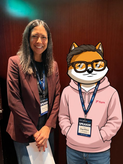 A woman wearing a maroon blazer and a 'SPEAKER' badge stands next to someone with an anime Shiba Inu avatar covering their face, also wearing a 'Hugo Pihlon / Founder' speaker badge.