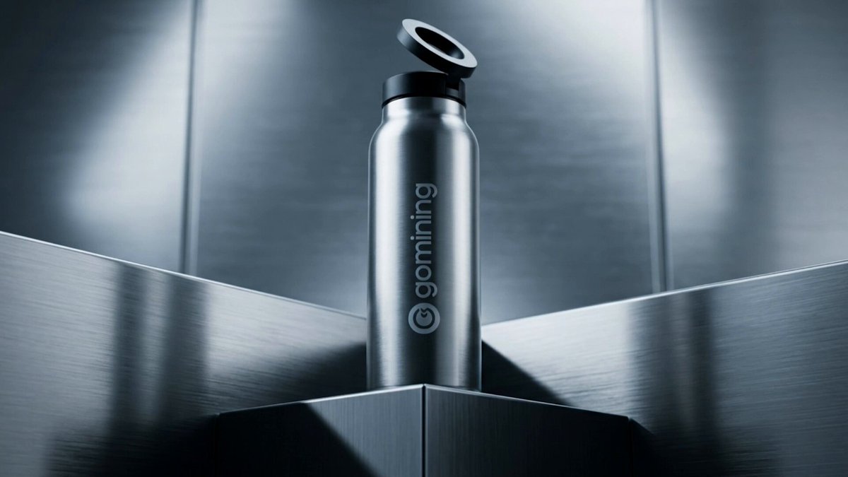 The image features a silver metal bottle with the word "GOMING" written on it. The bottle has an open top, suggesting that it might have been used or is being displayed for sale. The background of the image shows a metallic surface, possibly a wall or a countertop, which complements the silver color of the bottle and adds to its visual appeal.