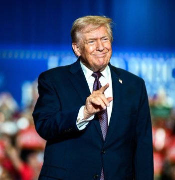 A man with blonde hair in a dark suit and striped tie points forward with a slight smirk at a campaign-style rally. The image relates to the post's message about the Trump administration pushing for the Clarity Act in the Senate, symbolizing a forward-moving political push.
