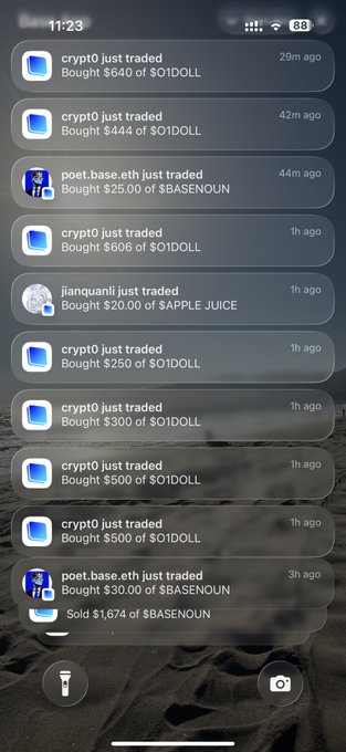 A smartphone notification feed displays a series of recent crypto trades, showing multiple "crypto just traded" alerts for $01DOLL purchases ranging from $250 to $640, along with poet.base.eth trading $BASENOUN, jianquani buying $APPLE JUICE, and a sale of $1,674 $BASENOUN—all timestamped within the last few hours, suggesting active trading activity on a memecoin wallet tracker app.