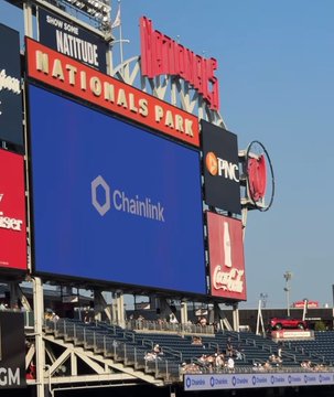 The image shows the Nationals Park scoreboard featuring a Chainlink (Chainlink Labs) advertisement, with "NATIONALS PARK" and the iconic "H" logo prominently displayed. The caption relates to the post's criticism of Chainlink ("Chainlink boys are desperate hypocrites") by highlighting the irony of a crypto/blockchain company buying stadium advertising space, as such corporate sponsorships have drawn scrutiny amid industry controversies.