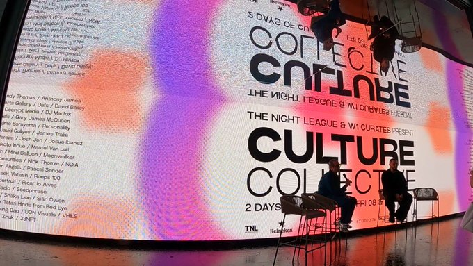 Two panelists sit on stage before a large digital screen promoting "CULTURE COLLECTIVE," a 2-day event presented by "THE NIGHT LEAGUE & W1 CURATES," with visible artist names like "James McQueen" and "Discipulus." The setup reflects the Bored Ape Yacht Club and OthersideMeta event mentioned in the caption, hosted in Ibiza.