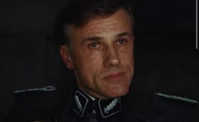 A close-up portrait of a man with short hair wearing a dark military uniform with collar insignia and shoulder boards.