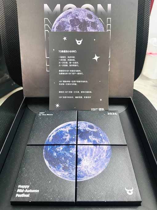 A black box displaying moon-themed artwork and a card with Chinese text, with "MOON" visible at the top and "XBIT" branding, along with "Happy Mid-Autumn Festival" text.