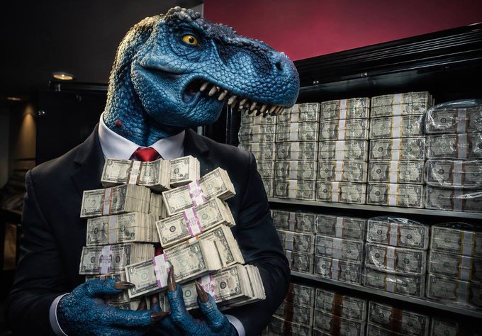 A person in a business suit wearing a blue velociraptor mask clutches stacks of banded U.S. dollar bills in front of a vault filled with currency. The image humorously visualizes the post's theme of aggressively deploying capital and "max bidding," depicting a "dino investor" amassing massive wealth with FEFER amid the "grave dancing."