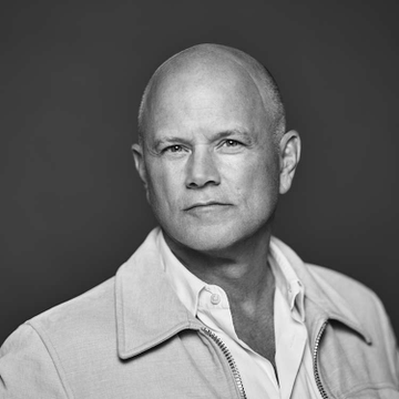 A black-and-white portrait of a bald man wearing a light-colored jacket over a white shirt, likely Mike Novogratz, the Galaxy Digital CEO referenced in the post discussing his Bitcoin price predictions.