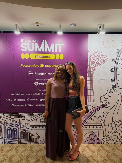 Two women posing for a photo in front of a purple event backdrop for the 'Solana Summit Singapore' featuring logos of sponsors including superteam, Frontier Trade, tethys, deBridge, EDGE, and others.