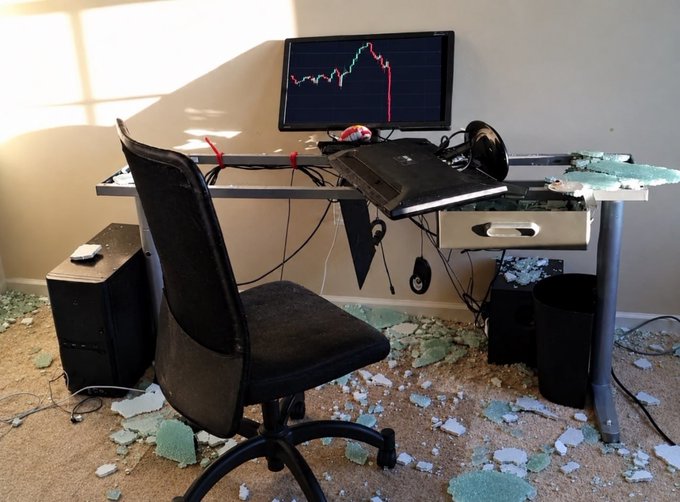 A home office desk setup with a monitor displaying a red stock chart showing a sharp decline, a laptop, a black office chair, and debris scattered across the floor, symbolizing a financial crash.