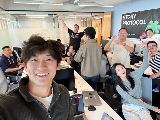 The image captures a lively office moment with the founding team of Story Protocol (now rebranded as DATA), including co-founders SY Lee and Jason Zhao, celebrating in a workspace with a "STORY PROTOCOL" banner visible in the background. Co-founders and team members are seen smiling, waving, and posing enthusiastically, reflecting the milestone of their rebranding journey—having raised $130 million, launched an EVM L1 blockchain, and issued the $IP token which reached an all-time high of $14.78 in September 2025.