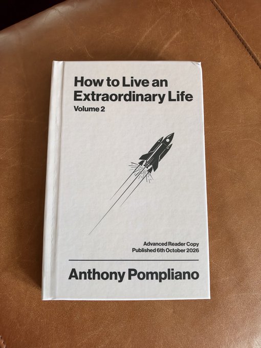 A copy of "How to Live an Extraordinary Life Volume 2" by Anthony Pompliano, an Advanced Reader Copy published 6th October 2026, featuring a rocket illustration on the cover, rests on a brown leather surface.
