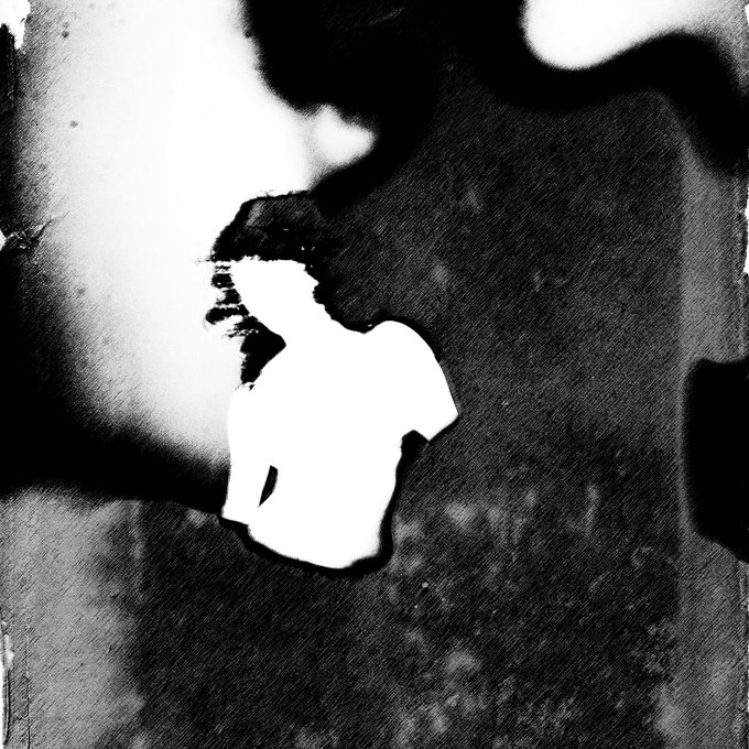 A heavily blurred and high-contrast black and white photograph shows a figure in a white shirt with a shadow of leaves falling across the scene.