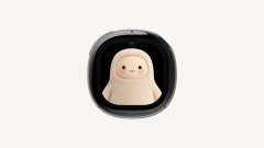 A small, stylized beige figure sits inside a glossy black, capsule-like pod against a white background.