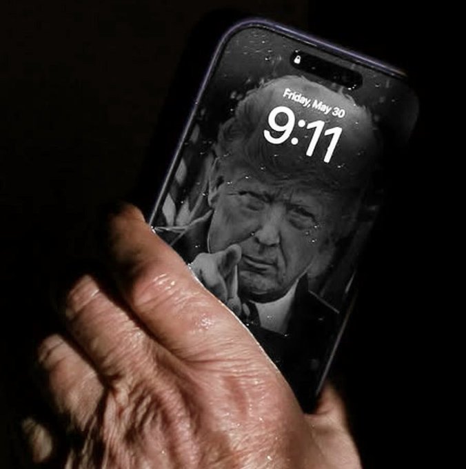 A hand holds a smartphone displaying a lock screen with a black-and-white image of Donald Trump, dated 'Friday, May 30' at 9:11.