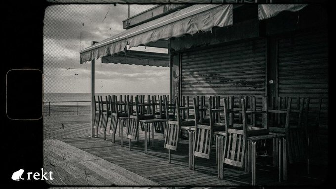 Rows of empty wooden chairs sit on a deserted boardwalk beside a closed seaside venue, evoking an abandoned and neglected atmosphere. The "rekt" watermark appears in the lower-left corner, tying the haunting scene of an empty, vulnerable setup to the post's message about crypto exploits being rooted in overlooked human and operational weaknesses rather than the code itself.
