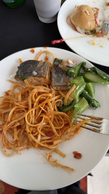 A partially eaten plate of spaghetti with tomato sauce, two square pieces of what appears to be a savory dish with greens, and sautéed snow peas, with a fork resting on the white plate.