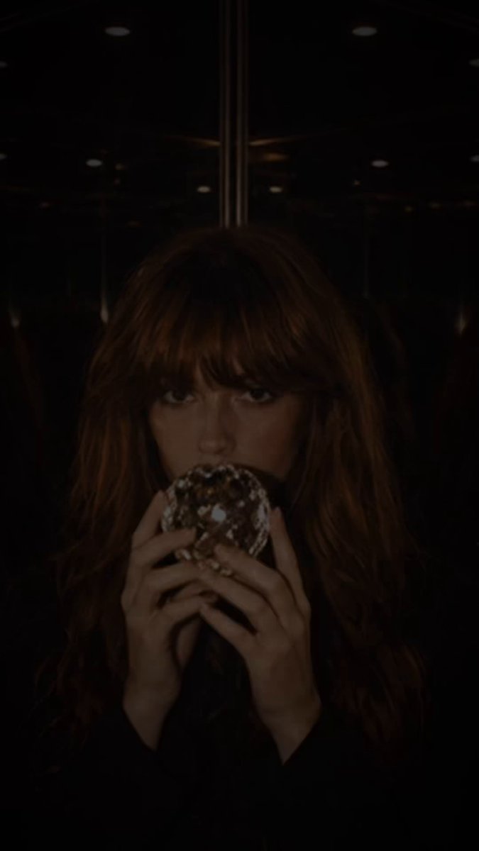 A young woman with long auburn hair and bangs holds a decorated donut to her mouth, her face partially illuminated against a dark background.

The post "DM to access" likely indicates that the image is being used as part of a gatekeeping or exclusive content prompt, where the user is being asked to send a direct message to receive further content, with the donut image serving as a teaser or hook.
