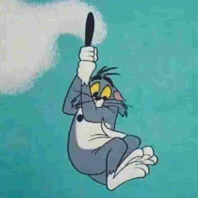 Tom from Tom and Jerry holds a baseball bat above his head in a swinging pose against a teal background.