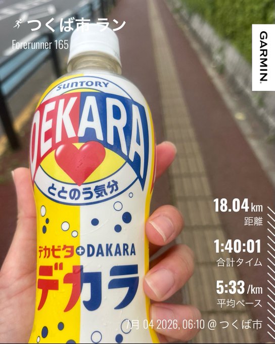 A hand holds a bottle of Suntory Dekavita C water with Japanese text including 'つくば市ラン' (Tsukuba City Run) and Garmin stats showing 18.04 km, 1:40:01 time, and 5:33/km pace on 7月04 2026.