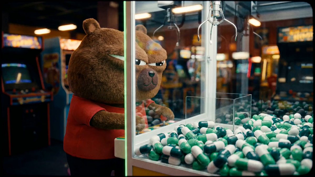 The image features a teddy bear standing next to a claw machine with green pills inside of it. A stuffed animal figure can be seen holding onto one of the pills as if they are trying to win at the claw game. The caption reads "In this game, conviction pays off. $BOBO".