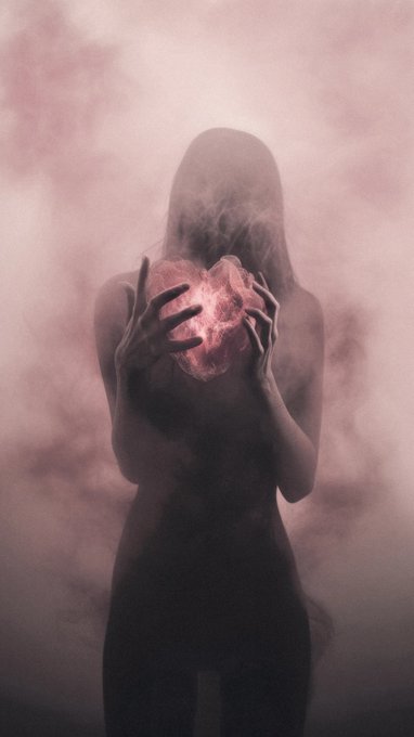 A dark, surreal image of a hooded figure holding a glowing red heart in front of their face, surrounded by smoky clouds.