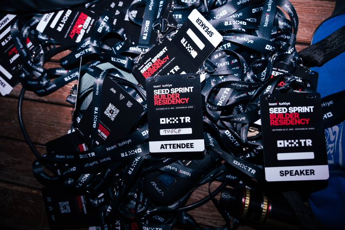 OKX TR Seed Sprint Builder Residency event badges/lanyards labeled 'ATTENDEE' and 'SPEAKER' piled together on a wooden surface.