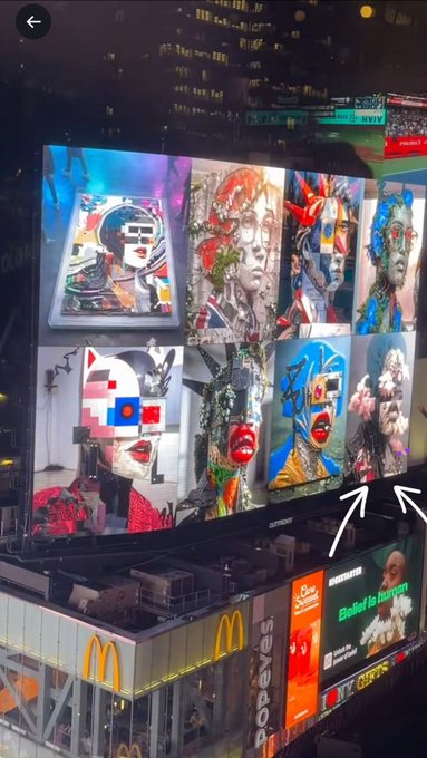 A nighttime view of a large digital billboard displaying a grid of colorful, abstract mixed-media portraits, with an arrow pointing toward the right side near a Popeyes and McDonald's sign below.