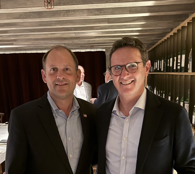 Two well-dressed men smile for a photo at what appears to be a business event, with the caption "$TEL making moves" suggesting the image captures executives from TE Connectivity (ticker $TEL) in a professional networking setting, possibly celebrating recent corporate developments or partnerships.