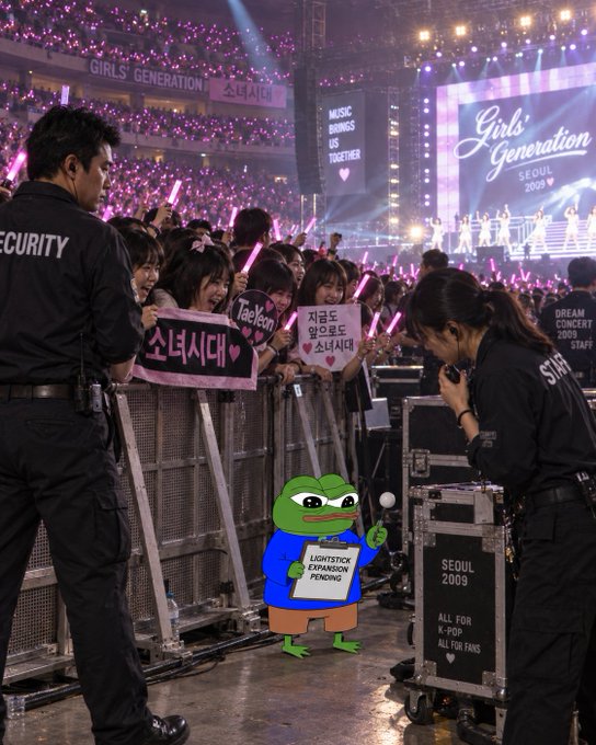 A K-pop concert scene showing fans holding signs for 'Girls' Generation' at the 'SEOUL CONCERT 2009', with a cartoon Pepe the Frog overlay holding a 'LIGHTSTOP EXPANSION PENDING' sign.