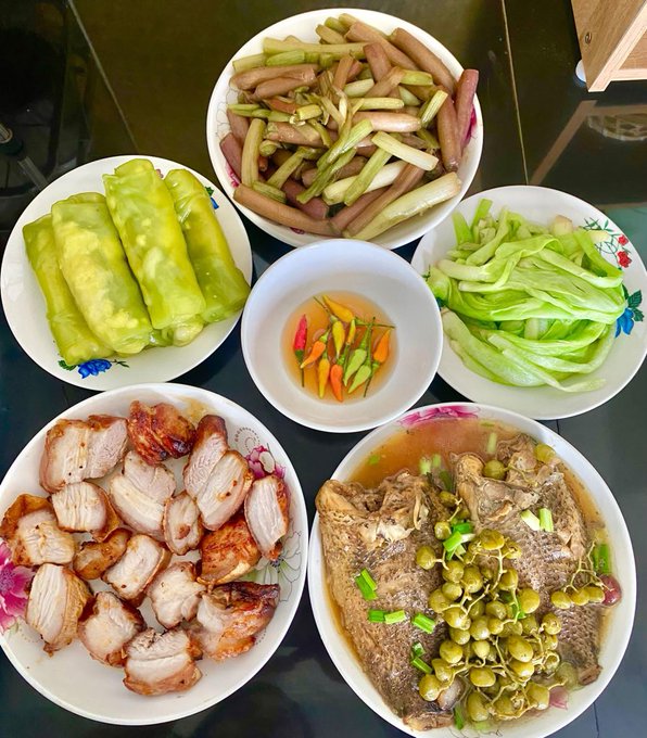 A spread of homemade Vietnamese dishes including stuffed cabbage rolls, braised pork, stir-fried vegetables, dipping sauce, and braised meat with green peppercorns.