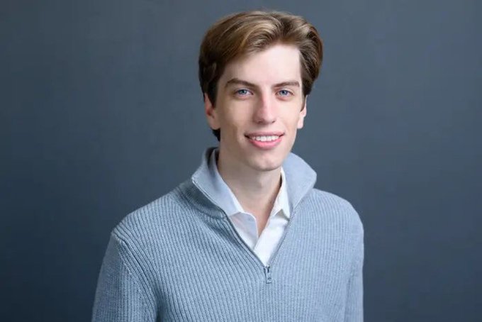 A smiling young man in a gray zip-up sweater over a white collared shirt poses against a dark background, with the post mocking the company for losing $45B in a month yet remaining unsatisfied.