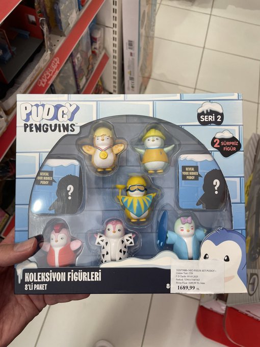A hand holds a "Pudgy Penguins Seri 2" collectible toy box priced at 1689.99 lira, featuring 8 figurines including surprise and special edition mystery figures, found unexpectedly at a small Turkish town store. The image illustrates the post's surprise of discovering Pudgy Penguins merchandise in a tiny city that doesn't even have a McDonald's or Starbucks.
