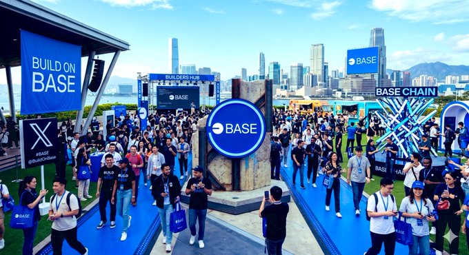 The image shows a large group of people walking around an event space, possibly at a convention or gathering related to cryptocurrency. The attendees are carrying backpacks and wearing name tags, indicating that they might be participants or organizers of the event. The backdrop features a city skyline with tall buildings, suggesting that the event is taking place in an urban setting. The image also contains text elements such as "Crypto is dead, nobody attends events anymore Meanwhile, at the BuildOnBase: Safe to say the BuildOnBase #POLY @base went crazy. Thank you to everyone who showed up to shape the future of the Onchain Economy."
