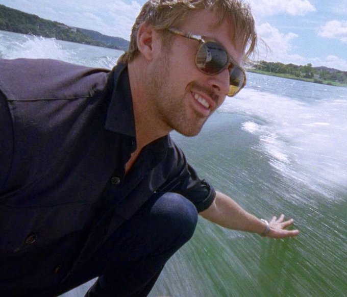 A smiling man with blonde hair and sunglasses crouches by the water's edge, reaching his hand toward the rushing wake of a boat. The image evokes the thrill and recklessness of risking it all, mirroring the post's caption about gambling with money you can't afford to lose.
