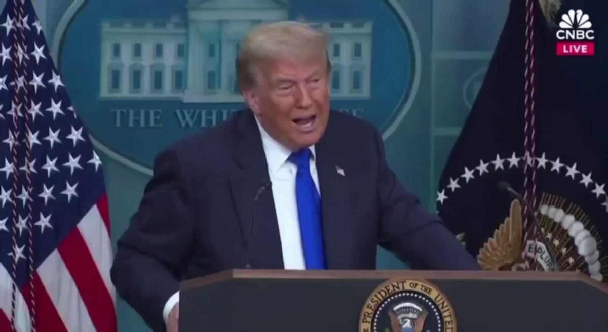 The image shows President Donald Trump standing at a podium, giving a speech or addressing an audience. The backdrop features two American flags, one on each side of the podium, symbolizing national pride and unity. The text "Bitcoin takes a lot of pressure off the dollar." suggests that Bitcoin has been used to invest in the US economy, potentially reducing the reliance on traditional currency systems like the US dollar.