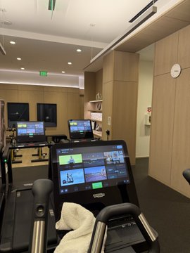 A row of Precor treadmills sits in a wood-paneled gym, with screens displaying workout options including "Pro Athlete Performance Run." The post "Back at it again day 6 I think" suggests the user is continuing their fitness routine for the sixth consecutive day.