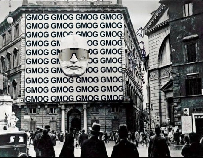 A black and white vintage street scene featuring a large billboard repeating the text 'GMOG GMOG GMOG', with a person wearing 'GMOG' sunglasses superimposed over a building facade.