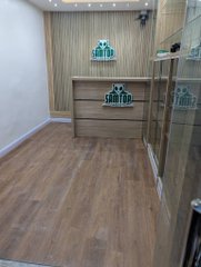 A modern, sleek office space features wood-look flooring, a decorative wooden panel wall with shelving, and glass doors, reflecting the newly opened Lagos location. The image celebrates the milestone of establishing a new physical workspace at Computer Village Ikeja, marking a significant step in the company's Web3 journey.