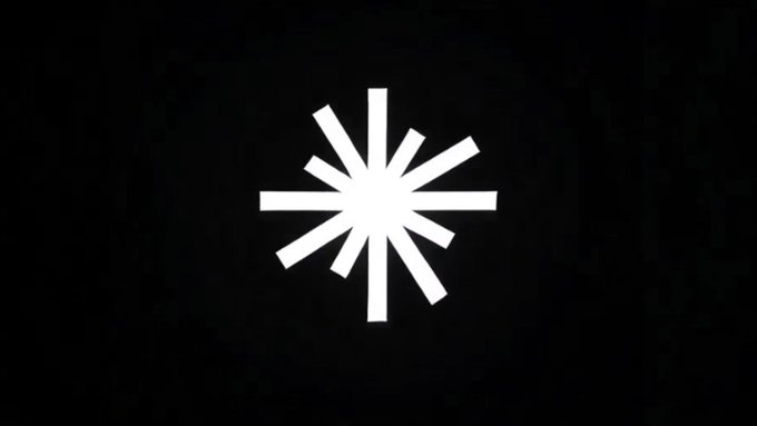 A white starburst or asterisk-like symbol centered on a black background. The minimalist icon likely represents Axis Robotics or a related loading/processing animation, symbolizing data processing and scaling discussed in the post about how increased contributors and simulations generate valuable training data.