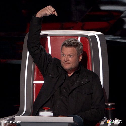 iced coffee and a black mug with white text are on the table, accompanied by a red chair and a man's arm raised in a thumbs up gesture.