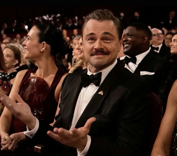 A man with a mustache in a tuxedo gestures with open hands and a smug smile at a formal event, mimicking the "this is fine" meme—perfectly capturing the laid-back confidence of someone whose Bitcoin investments are quietly growing while others question the strategy.