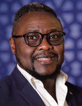 A smiling man with glasses, a goatee, and a dark blazer over a white shirt poses against a blue geometric background. The professional portrait pairs with the caption "Who is Pepe?" to introduce the individual featured.