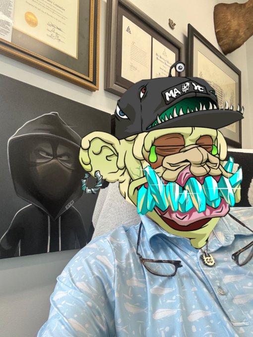A person wearing a blue whale-patterned shirt in an office setting, overlaid with an animated Pepe-style frog meme wearing a black 'MARE YE' cap, displaying dripping green and blue teeth effects, with framed certificates and a hooded figure in the background.