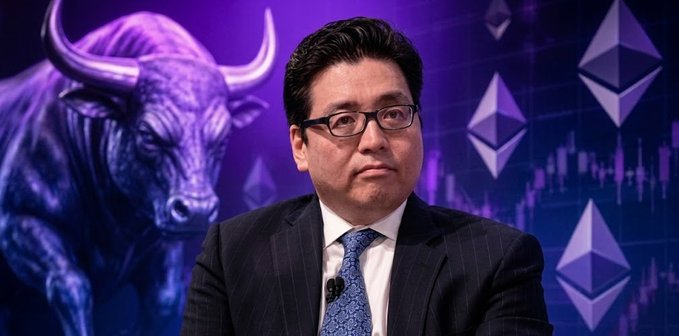 A man in a dark pinstripe suit and blue tie is shown in front of a backdrop featuring a purple bull and Ethereum logos, suggesting a financial or cryptocurrency broadcast.