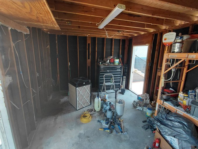 A cluttered, unfinished garage/workshop space undergoing conversion into a "Mining Shed," featuring exposed wooden framing, drywall backing, and scattered tools including drills, pliers, and a Husky tool chest, alongside one operational S21 miner currently being deployed to assist with DigiByte ($DGB) upgrades.