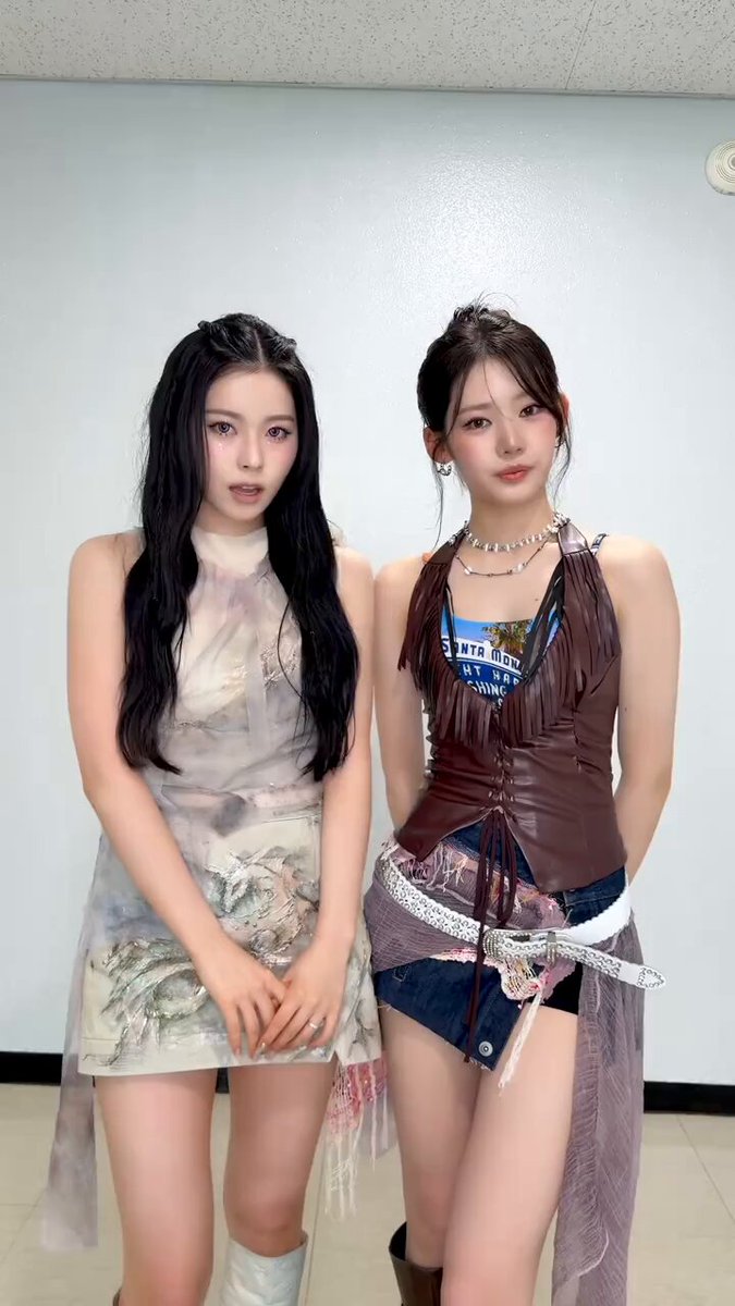 The image features two young women posing for a photo together, both wearing dresses with fringes. The background of the picture appears to be a white wall or a gray room. There are also some text elements present in the image that read "6.01梭哈晨报", "1. $BTC 美股期货开盘后", and "2. $ETH 看起来好点", which could be related to the dresses or possibly a reference to an event, product, or artist featured in the image.