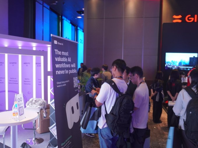 Attendees at a tech event walk past a Ghost AI booth displaying the text 'The most valuable AI workflows will never be public.'