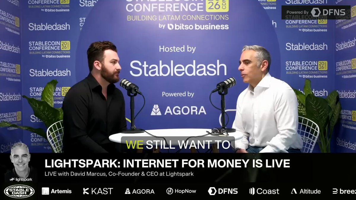 The image features a man sitting at a table with another person, both of them wearing white shirts. They are talking about the importance of having a strong online presence for businesses.